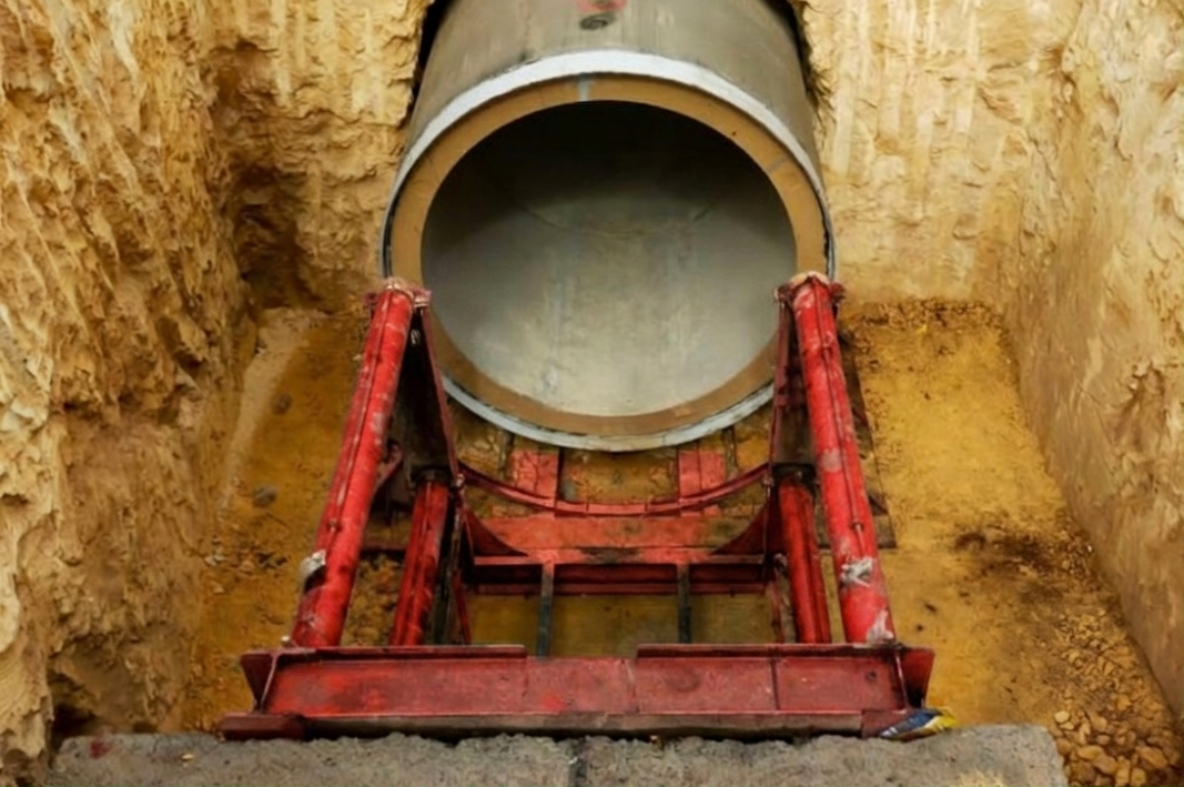 Vue de dessus d'un puits de fonçage horizontal montrant les vérins hydrauliques poussant une conduite en béton